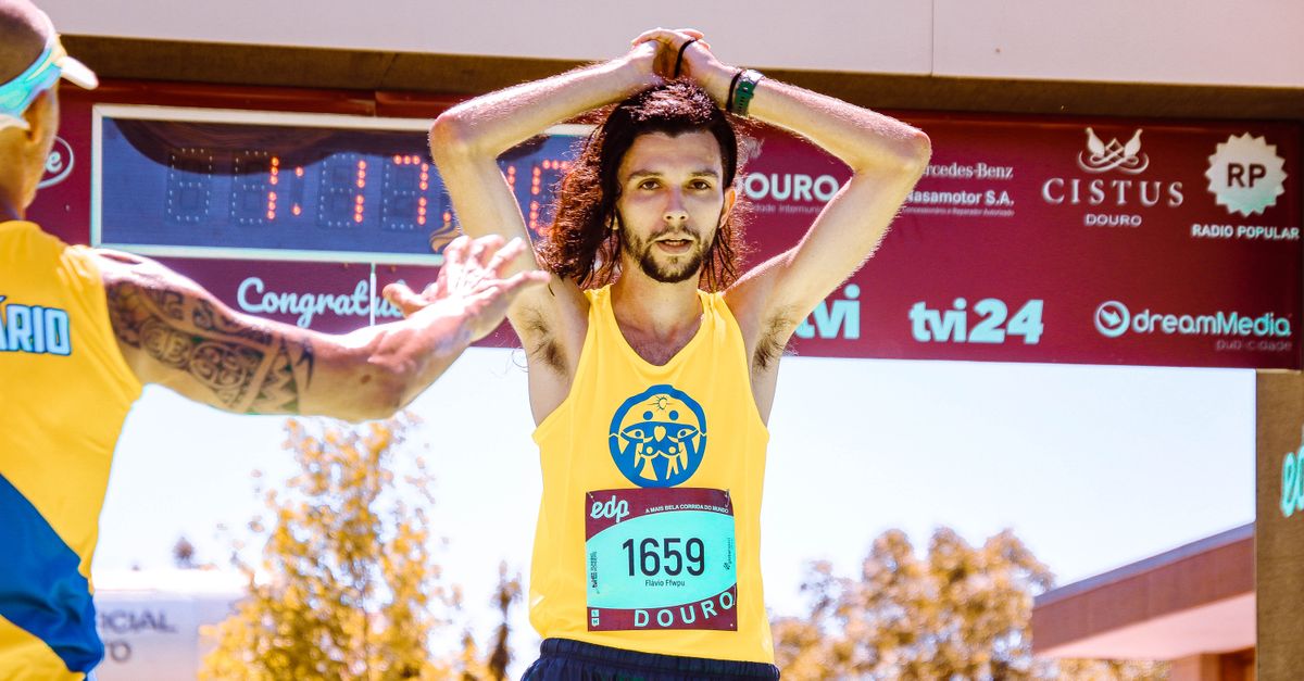 Exhausted marathon runner crossing the finish line triumphantly under sunny skies.